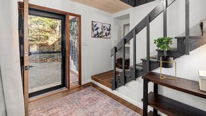 A modern interior with a wooden staircase, a glass door leading outside, and a small table with a plant.