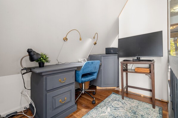 A modern office space with a desk, chair, and TV.