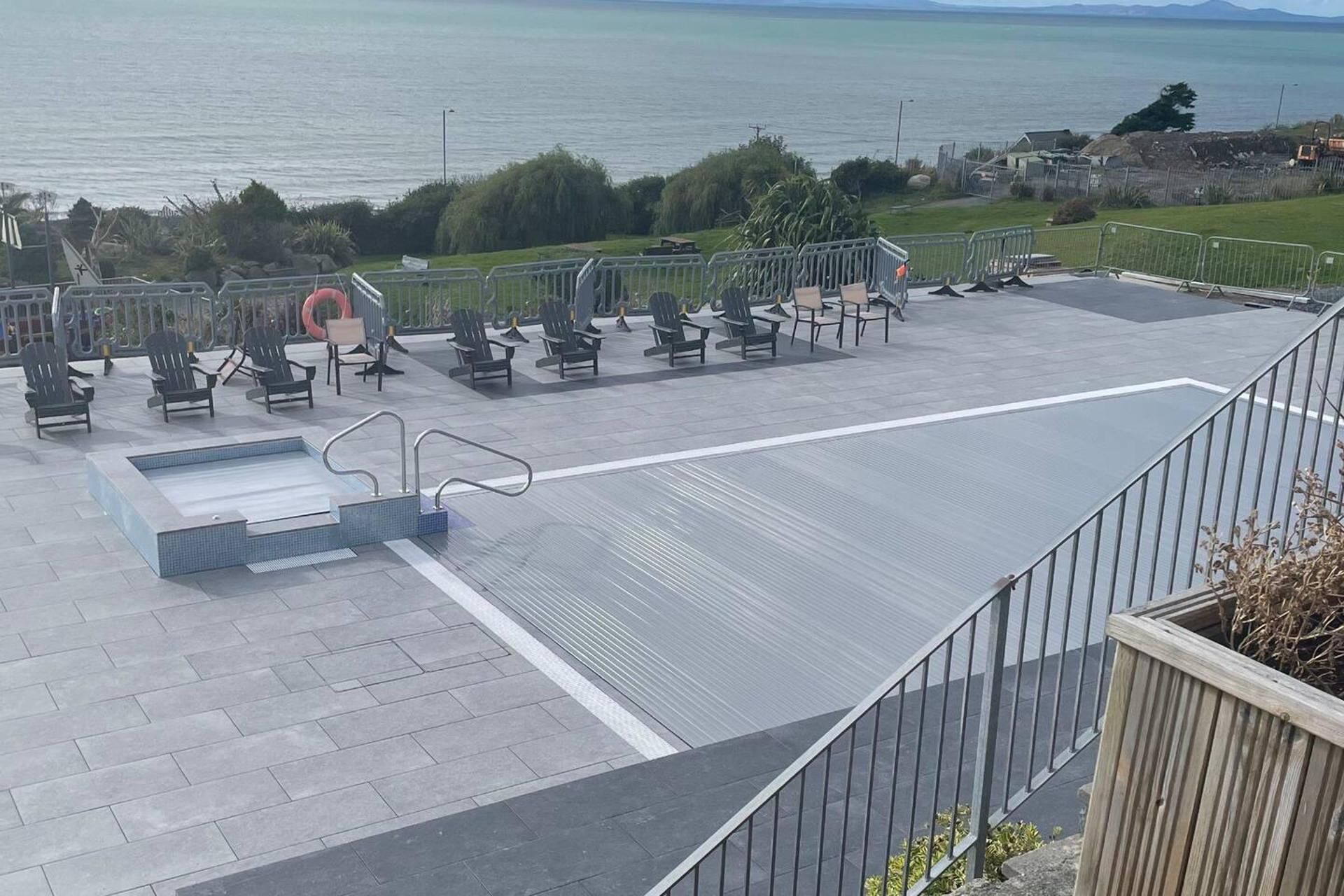 Een terras aan het water met zitplaatsen buiten en een zwembad.