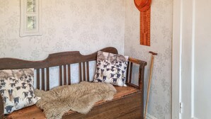 A wooden bench with patterned cushions, a rustic wooden floor, and a cane leaning against the wall.