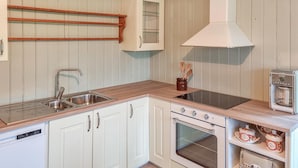 A compact kitchen with white cabinetry, a stainless steel sink, a built-in oven, and a coffee machine.