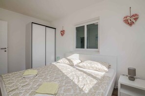 A bedroom with a bed, a nightstand, a window, and a wardrobe.