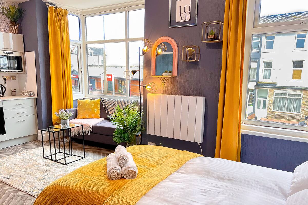 Habitación de hotel moderna con una cama grande, un sofá, un comedor y vistas a la ciudad.