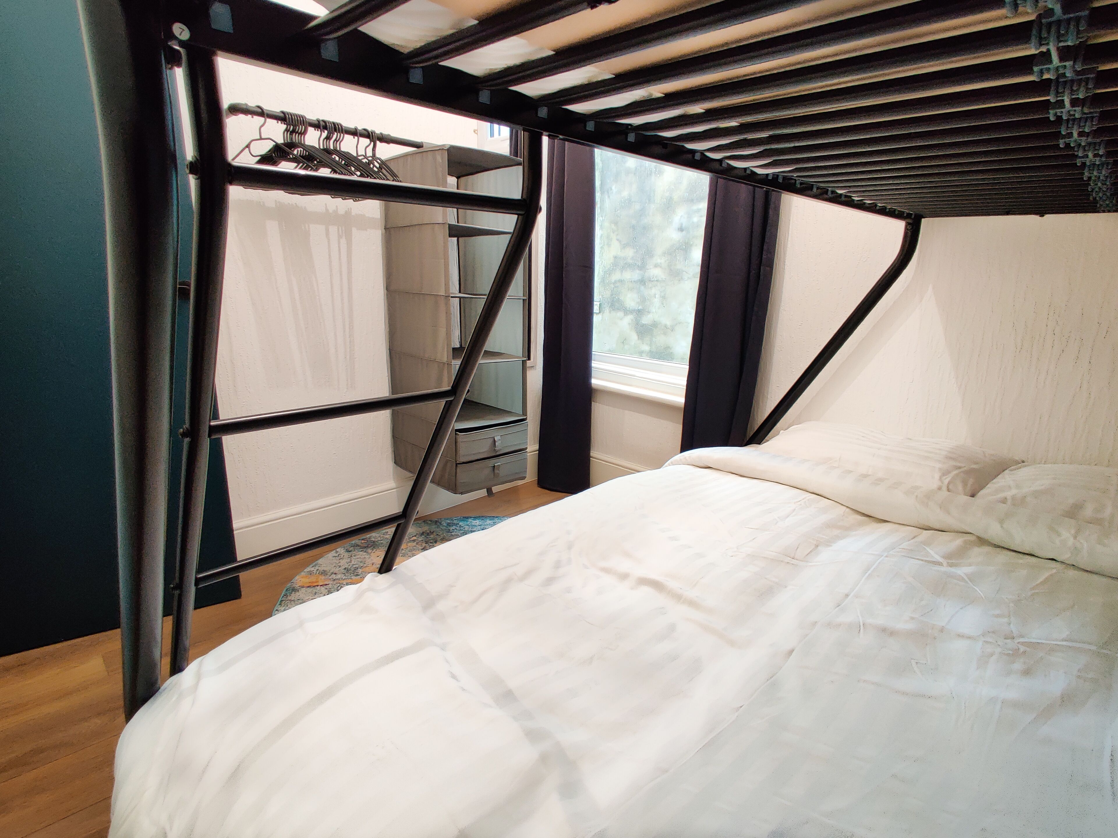 A bedroom with a bed, a wardrobe, and a window.