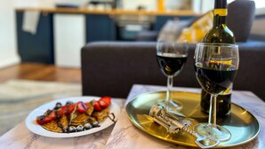 Una mesa de comedor con un plato de comida, dos copas de vino tinto y una botella de vino sobre una bandeja.