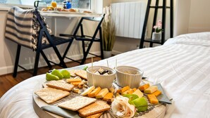 Bandeja de desayuno con queso, galletas y frutos secos sobre la cama en una habitación de hotel.