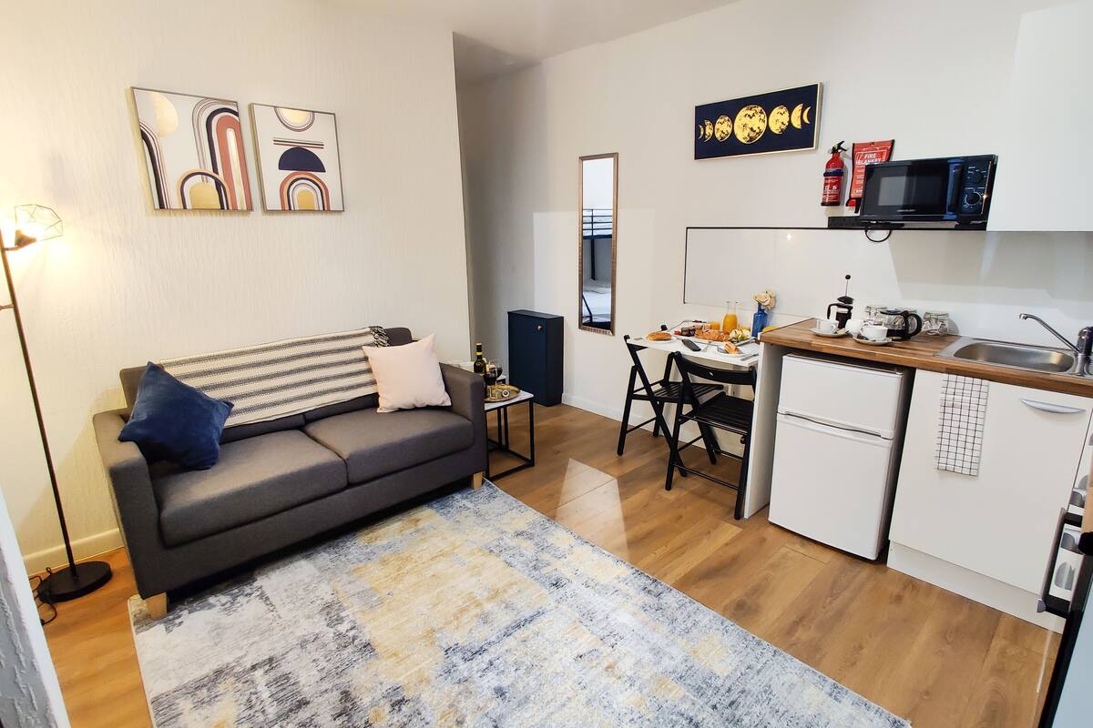 Un espacio habitable compacto con sofá, mesa de comedor y kitchenette.