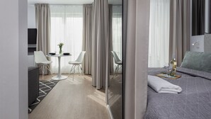 Een moderne hotelkamer met een bed, een zithoek met een tafel en stoelen, en een televisie.