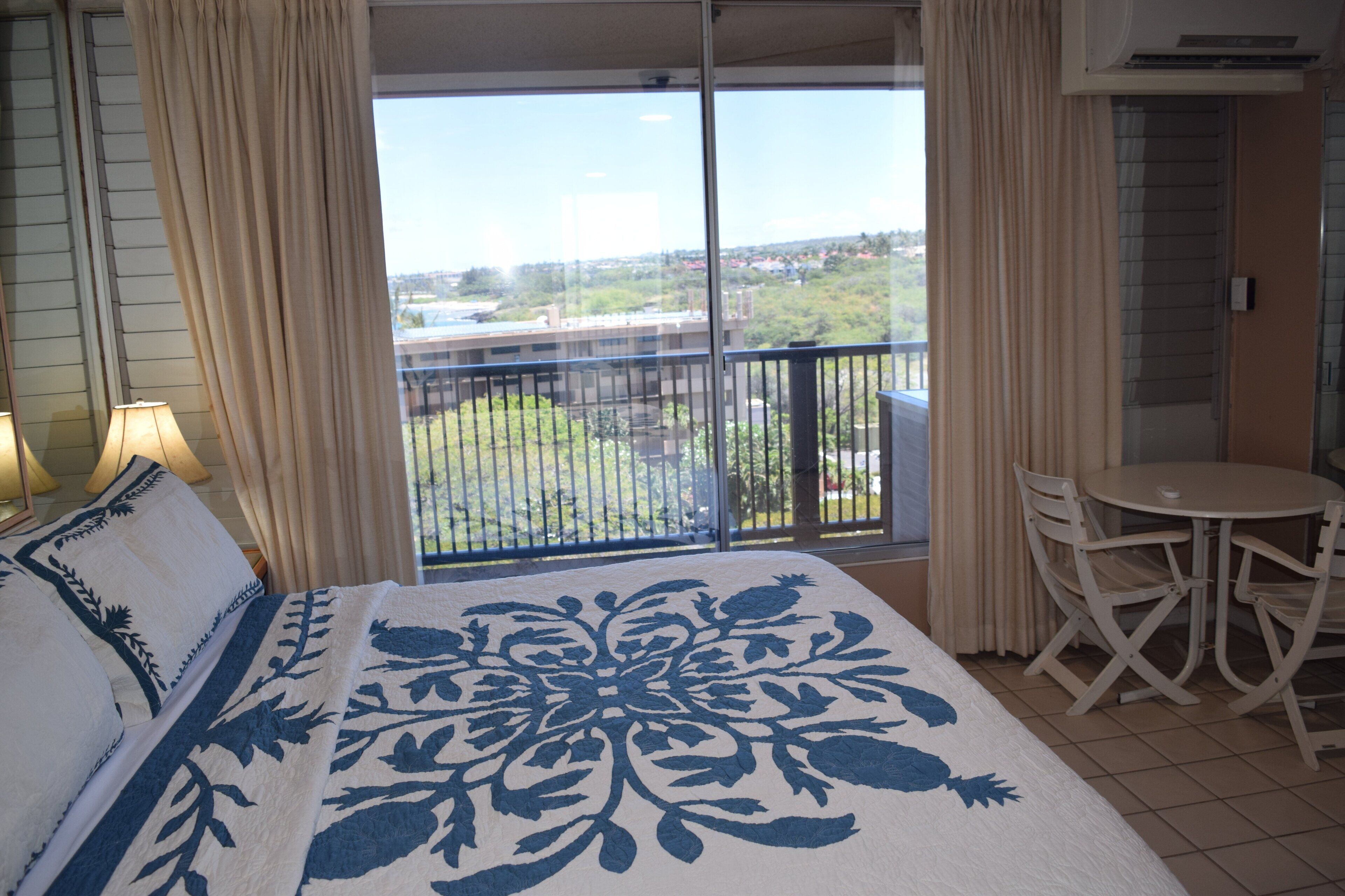 Ein Hotelzimmer mit einem großen Bett, einem Balkon mit Blick, einem kleinen Tisch und Stühlen.