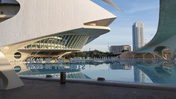 A modern architectural structure with a pool in the foreground and a cityscape in the background. - port of valence (València)