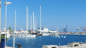 A waterfront promenade with a marina in the background, featuring boats and cranes. - port of valence (València)