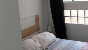 A bedroom with a bed, a window with curtains, and a ceiling light. - port of valence (València)