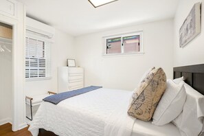 Une chambre à coucher avec un lit, une fenêtre, une armoire et une petite table.