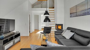 A modern living room with a black sofa, a TV, and a fireplace. - Nice apartment in Bogense with WiFi (Bogense)