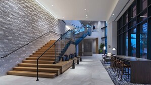 Un hall d’entrée moderne avec un escalier, un espace salon et de grandes fenêtres.