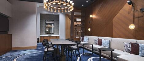 A modern hotel room with a dining area, a sofa, a small table, and a chandelier.