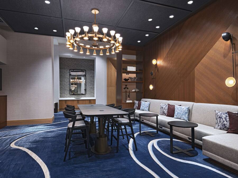 A modern hotel room with a dining area, a sofa, a small table, and a chandelier.