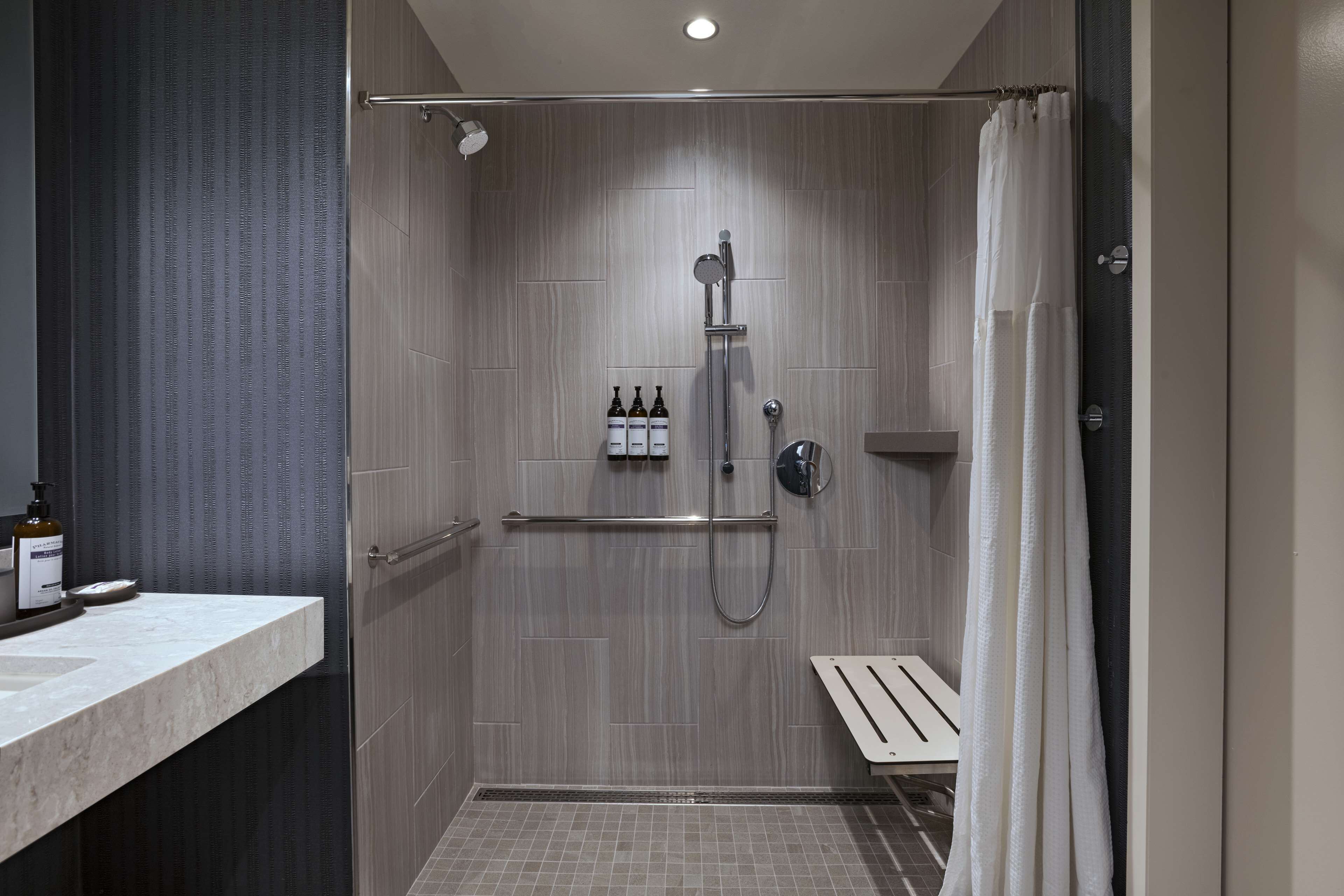 A modern bathroom with a shower, a towel rack, and a small shelf with toiletries.