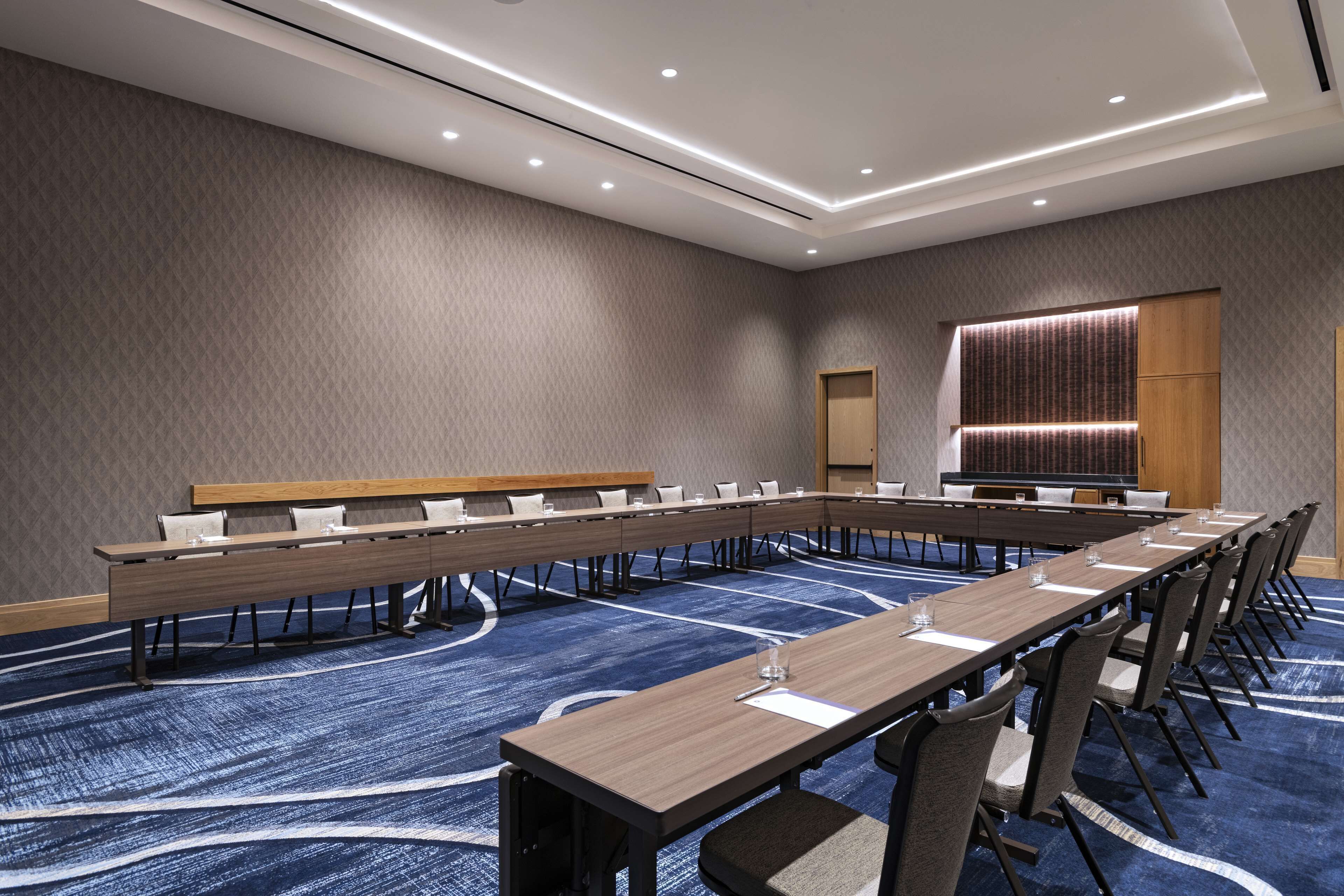 Une salle de conférence avec une longue table, des chaises et un sol recouvert de moquette.