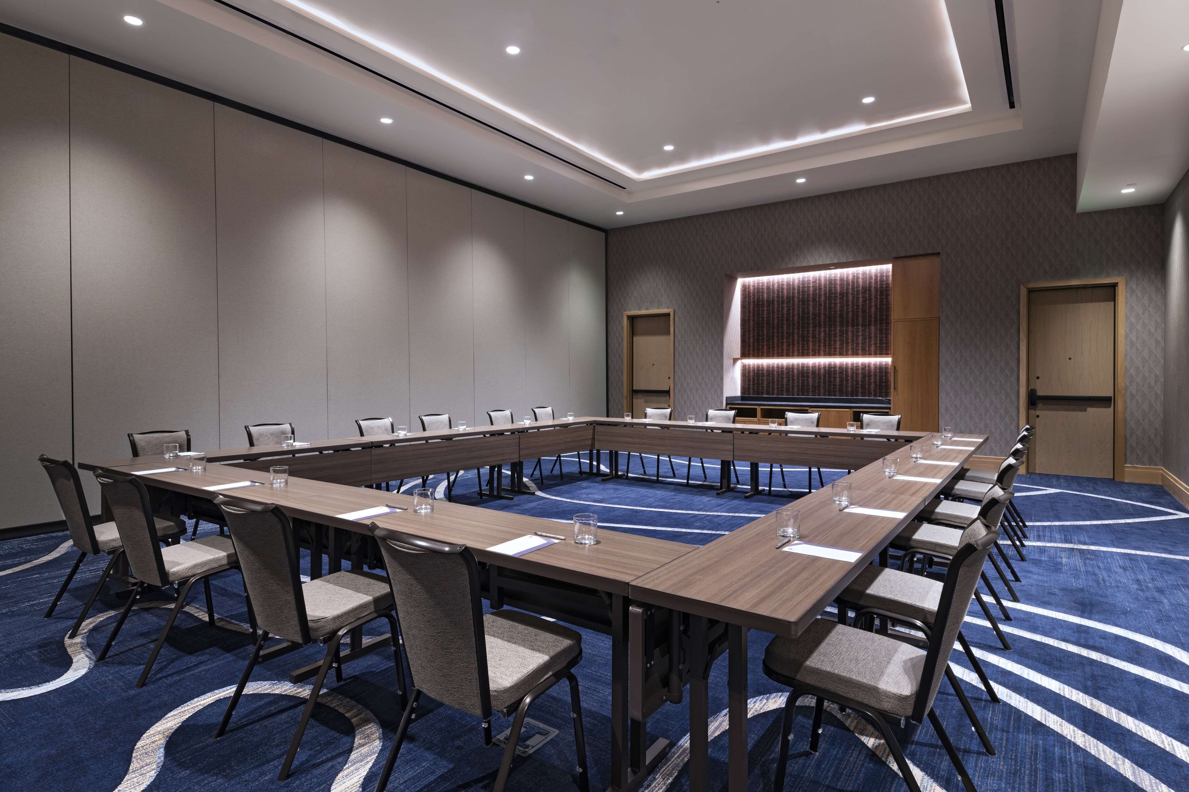 A conference room with a long table, chairs, and a carpeted floor.