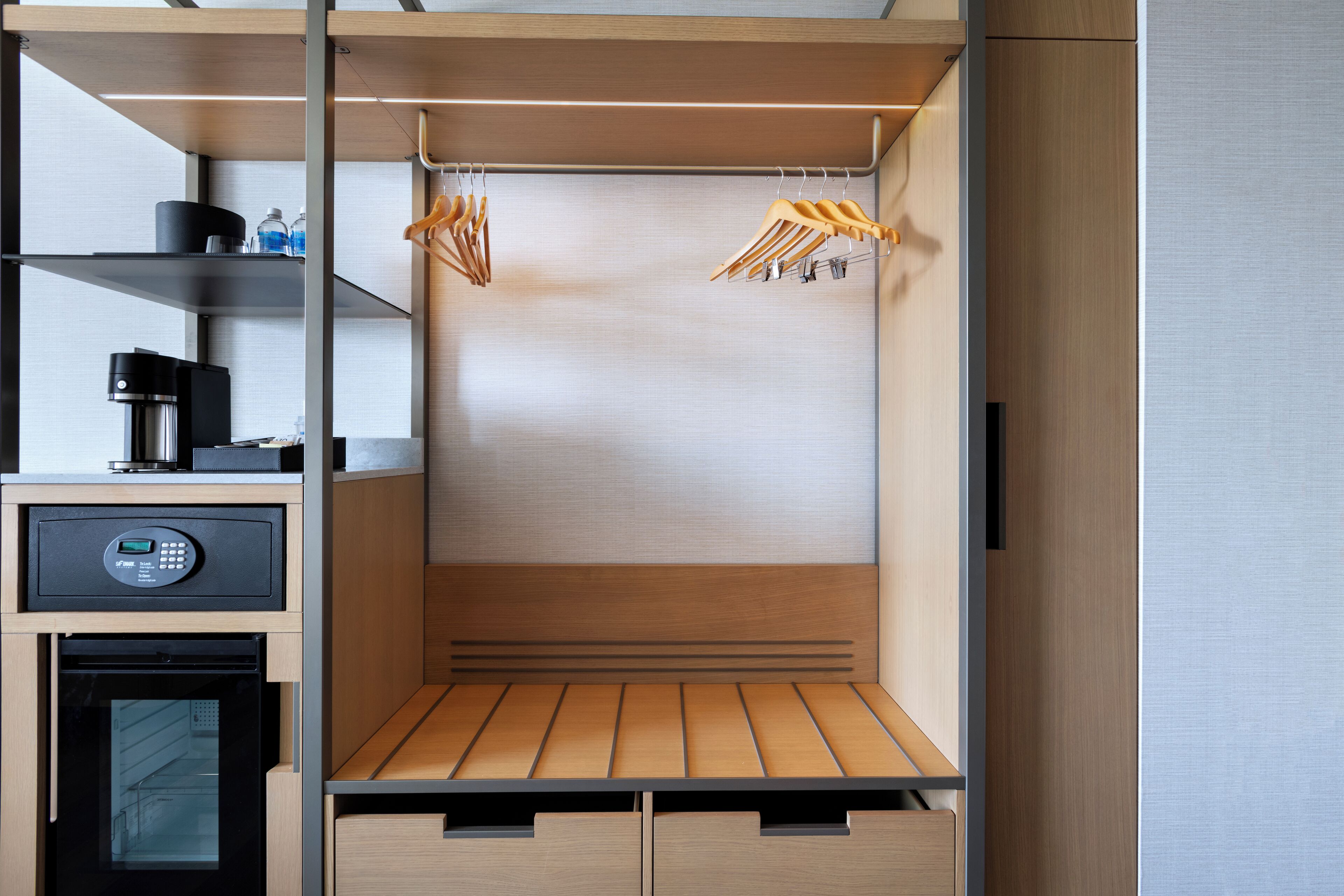 Una kitchenette compacta con cafetera, microondas y refrigerador pequeño.