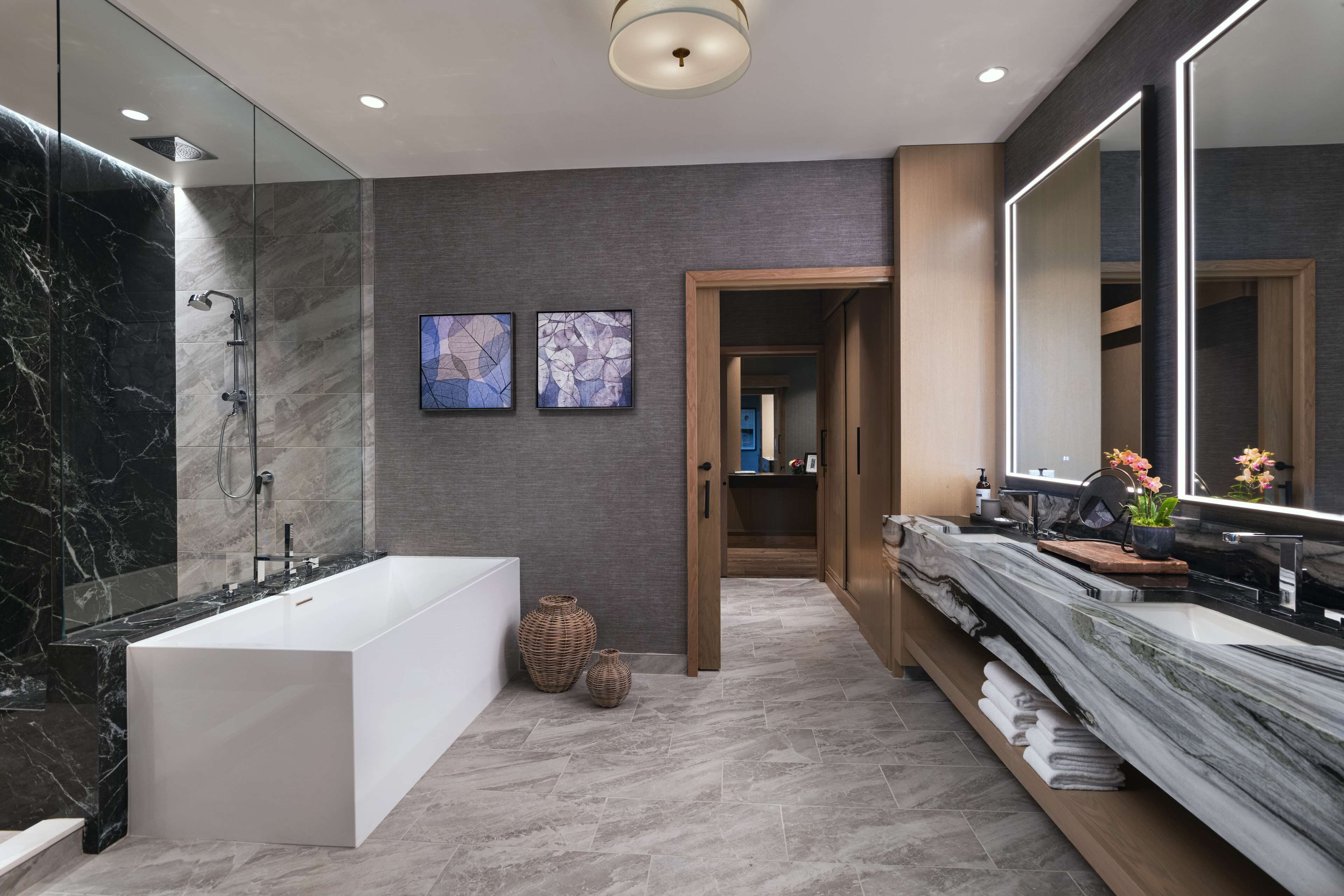 Une salle de bain moderne avec une grande baignoire, une douche à l’italienne avec des parois en verre et un comptoir en marbre.
