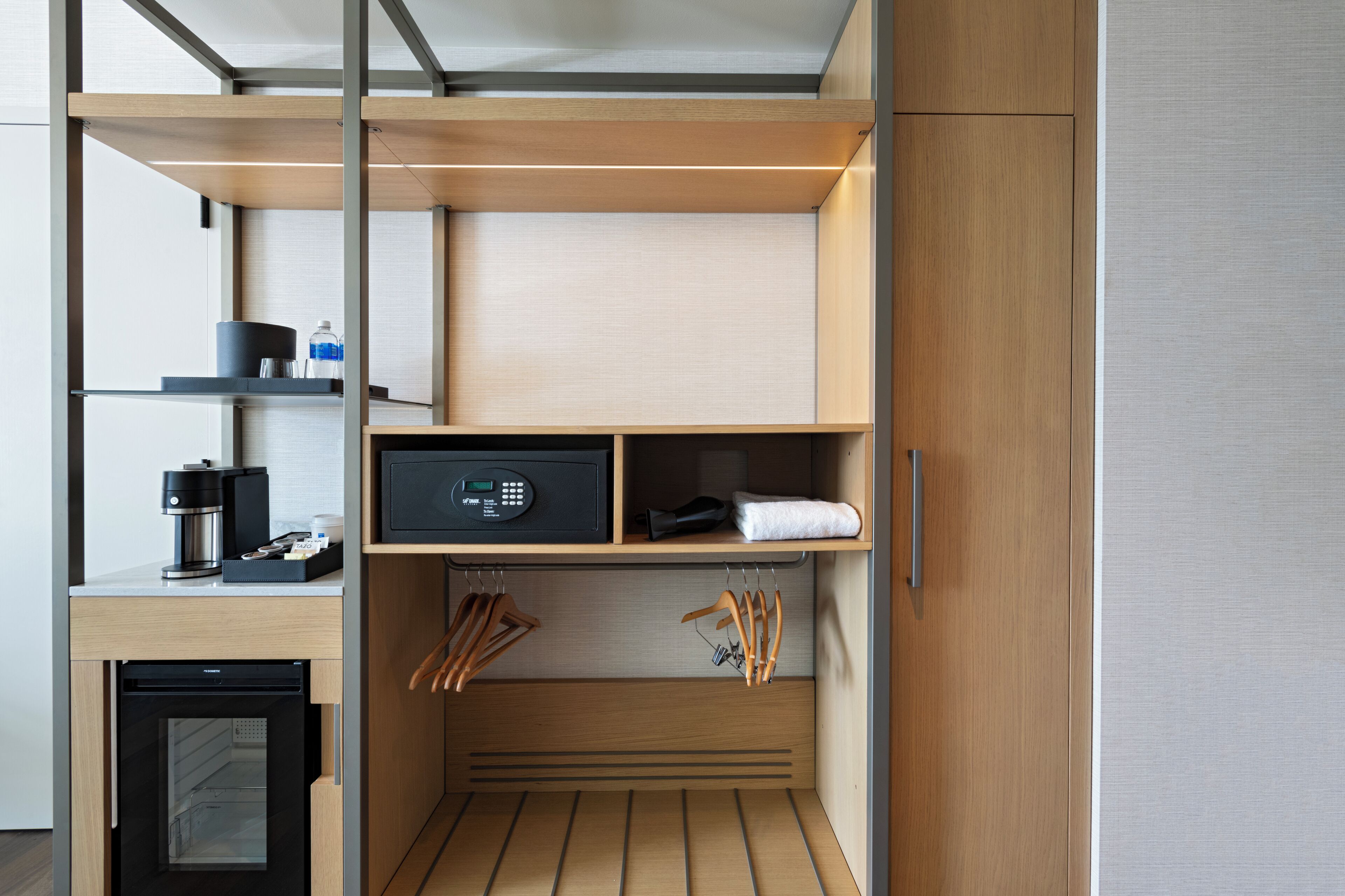 A compact kitchenette with a coffee maker, microwave, and storage shelves.