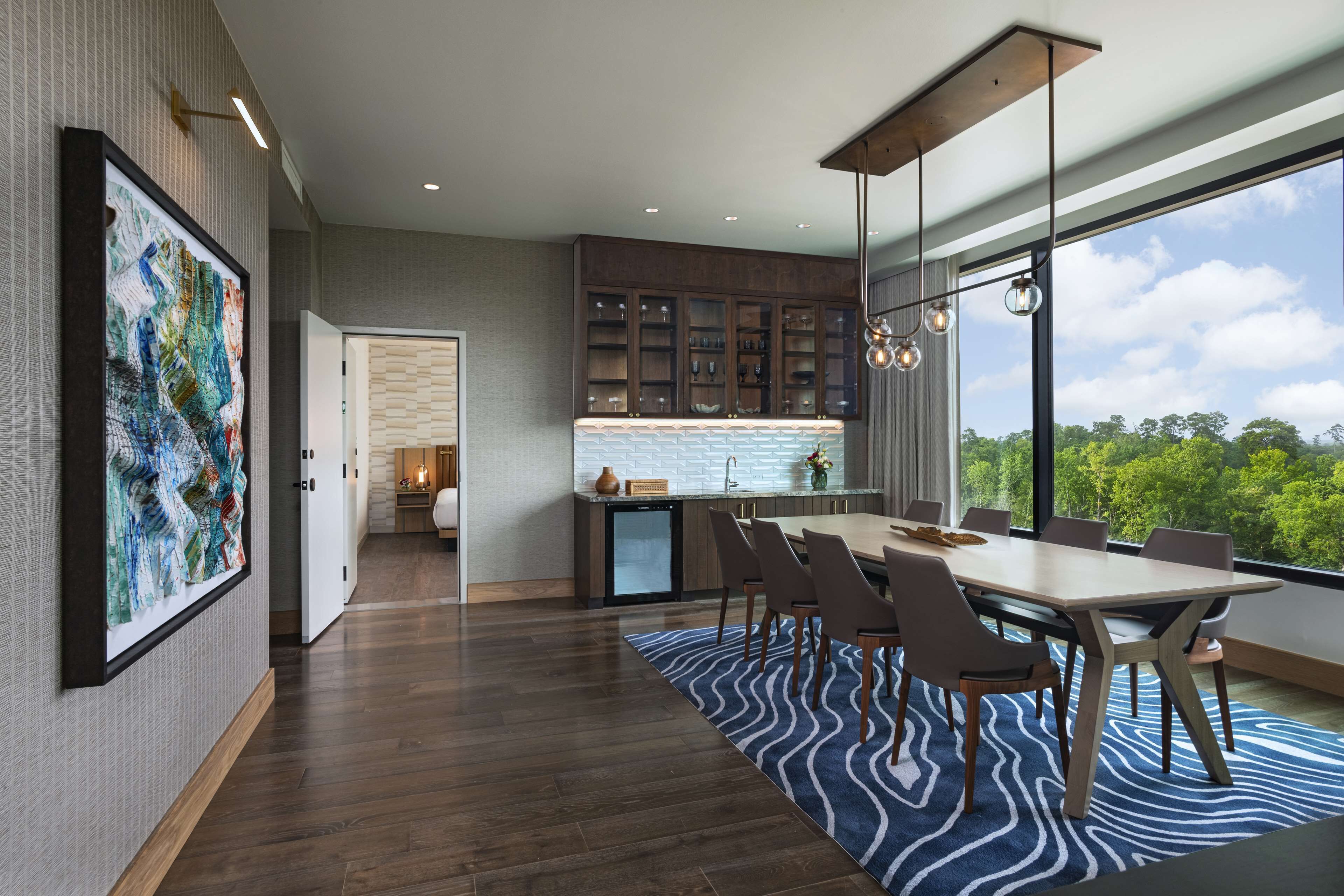 A modern kitchen with dark cabinetry, a built-in island, and a large window offering a view of greenery.