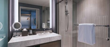 A modern bathroom with a glass-enclosed shower, a vanity with a mirror, and a towel rack.