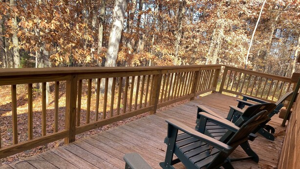 A wooden deck with two Adirondack chairs and a wooden railing. - Perfect Cabin for Fisherman and Families (French Lick)