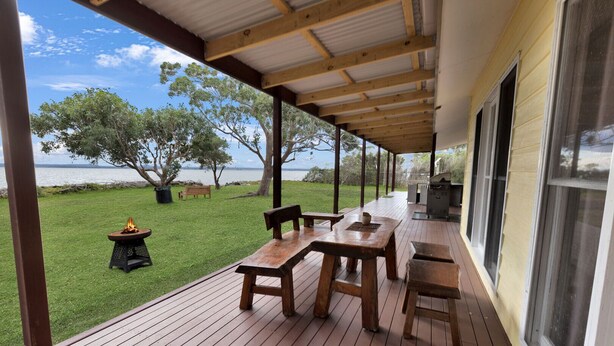 A covered outdoor deck with wooden furniture, a grill, and a fire pit. - Tranquility Point: Perfect for those looking to enjoy some peace (Raymond Island)