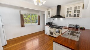 A kitchen with wooden flooring, white cabinets, a stove, a microwave, and a sink. - Tranquility Point: Perfect for those looking to enjoy some peace (Raymond Island)