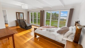 A spacious bedroom with a large bed, a massage chair, and a view of the outdoors. - Tranquility Point: Perfect for those looking to enjoy some peace (Raymond Island)