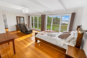 A spacious bedroom with a large bed, a massage chair, and a view of the outdoors. - Tranquility Point: Perfect for those looking to enjoy some peace (Raymond Island)