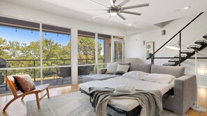 Un dormitorio moderno con una cama grande, un sofá, una silla y una escalera.
