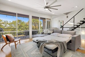 A modern bedroom with a large bed, a sofa, a chair, and a staircase.