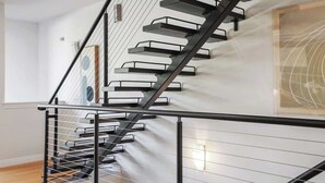Una escalera moderna con barandilla de metal negro y paredes blancas.