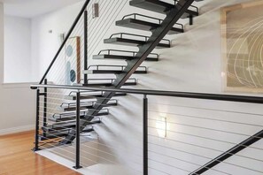 A modern staircase with a black metal railing and white walls. - Noble Nest - 5 Min to Downtown and U of A (Fayetteville)
