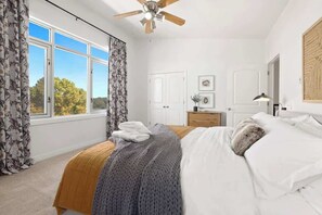 A bedroom with a bed, a ceiling fan, a window with curtains, a dresser, and a door. - Noble Nest - 5 Min to Downtown and U of A (Fayetteville)