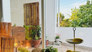 A patio area with a wooden table, potted plants, and a tiered stand with lemons. - Palm View Guesthouse-Adults only (Lagos)