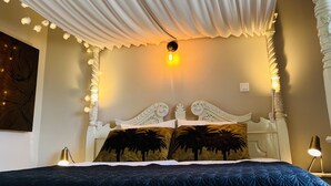 A bedroom with a canopy bed, a nightstand, and a wall-mounted lamp. - Palm View Guesthouse-Adults only (Lagos)