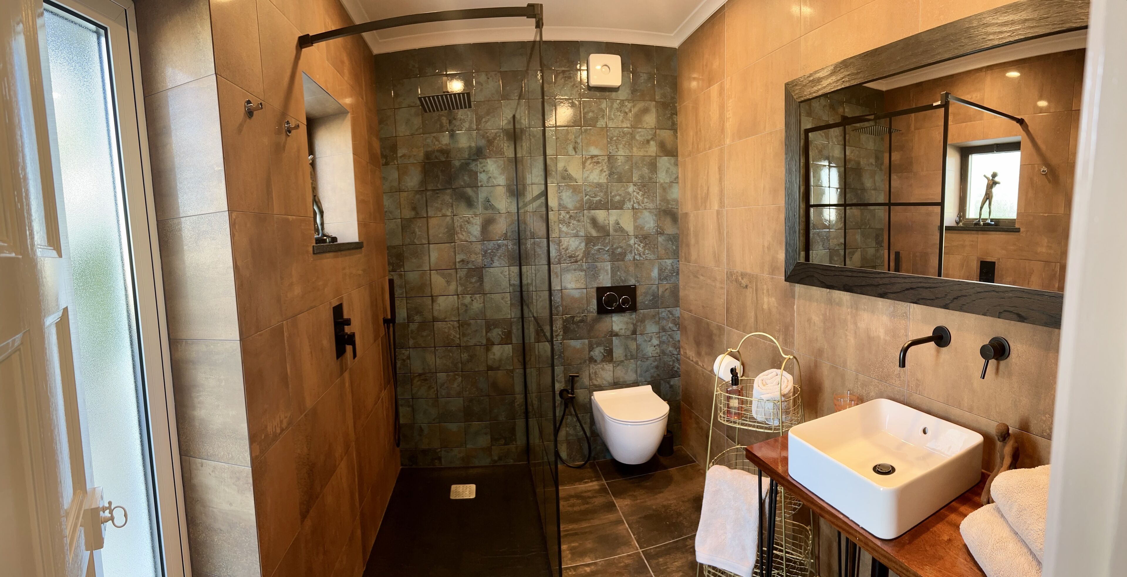Une salle de bain moderne avec une douche à parois de verre, des toilettes blanches, un lavabo avec un miroir et un porte-serviettes.