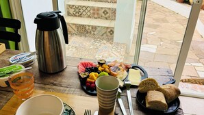 A dining table with a variety of food items, a coffee pot, and a view of a staircase leading to an outdoor area with plants. - Palm View Guesthouse-Adults only (Lagos)
