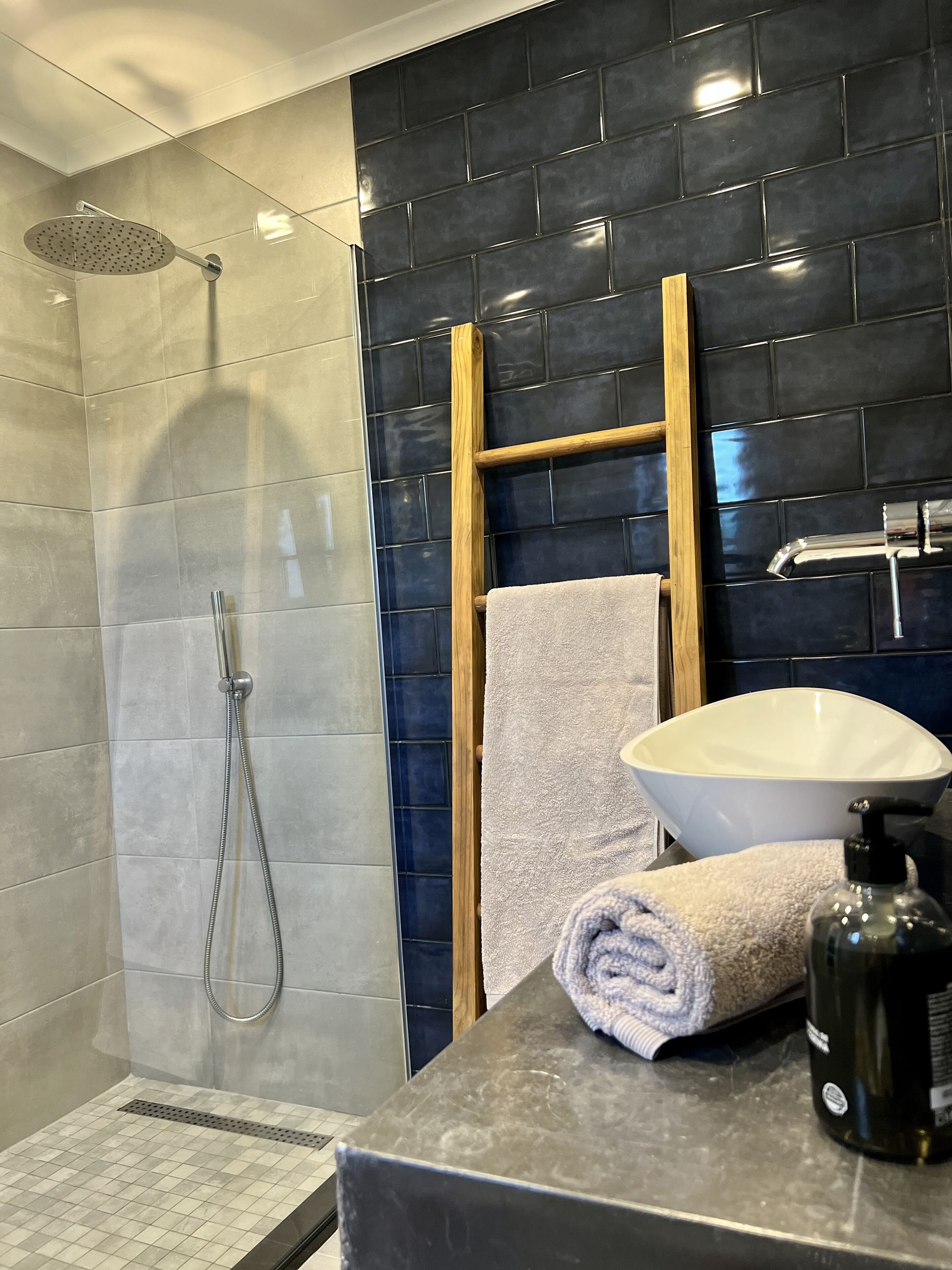 Un baño moderno con ducha, lavamanos y una escalera de madera.