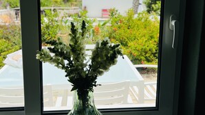 A window with a clear view of a white table and chairs, a green vase with foliage, and a rock decoration. - Palm View Guesthouse-Adults only (Lagos)