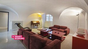 A modern living room with a sofa set, a coffee table, and a lamp. There is a piano in the background and a radiator on the wall. - Garibaldi Glamorous Apartment by Wonderful Italy (Genova)