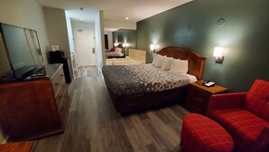 Habitación de hotel con cama, escritorio, silla, televisor y baño a la vista.