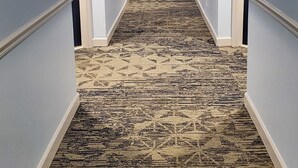 Un pasillo largo y estrecho con alfombra estampada y paredes azul claro.