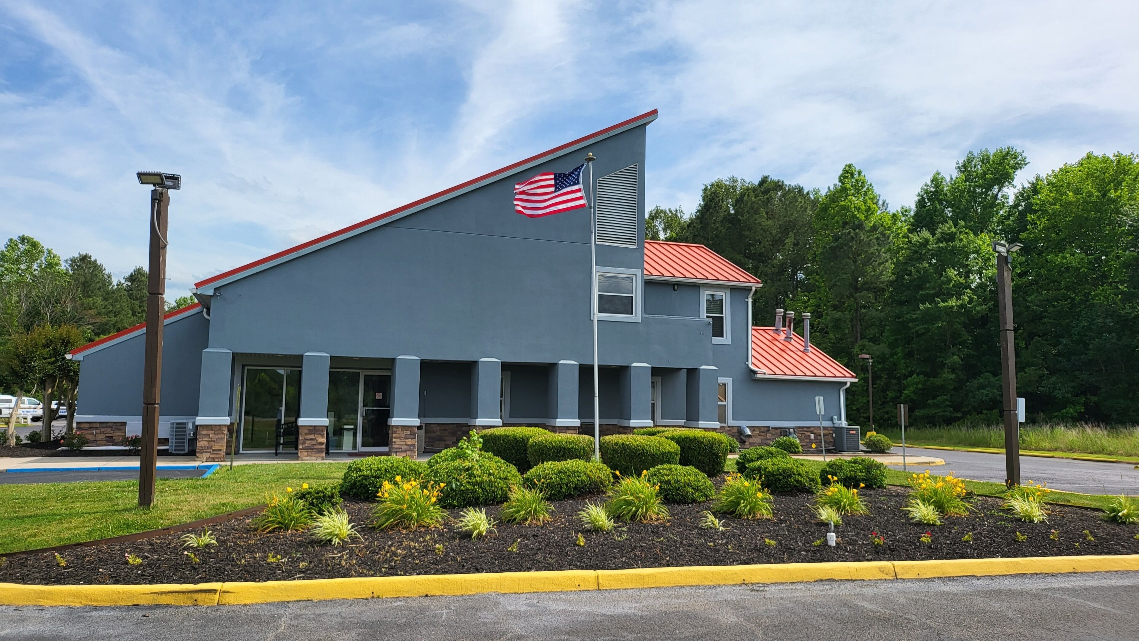 A two-story building with a red roof and an American flag on the side.