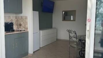 A compact kitchen with grey cabinets and a blue wall-mounted TV.